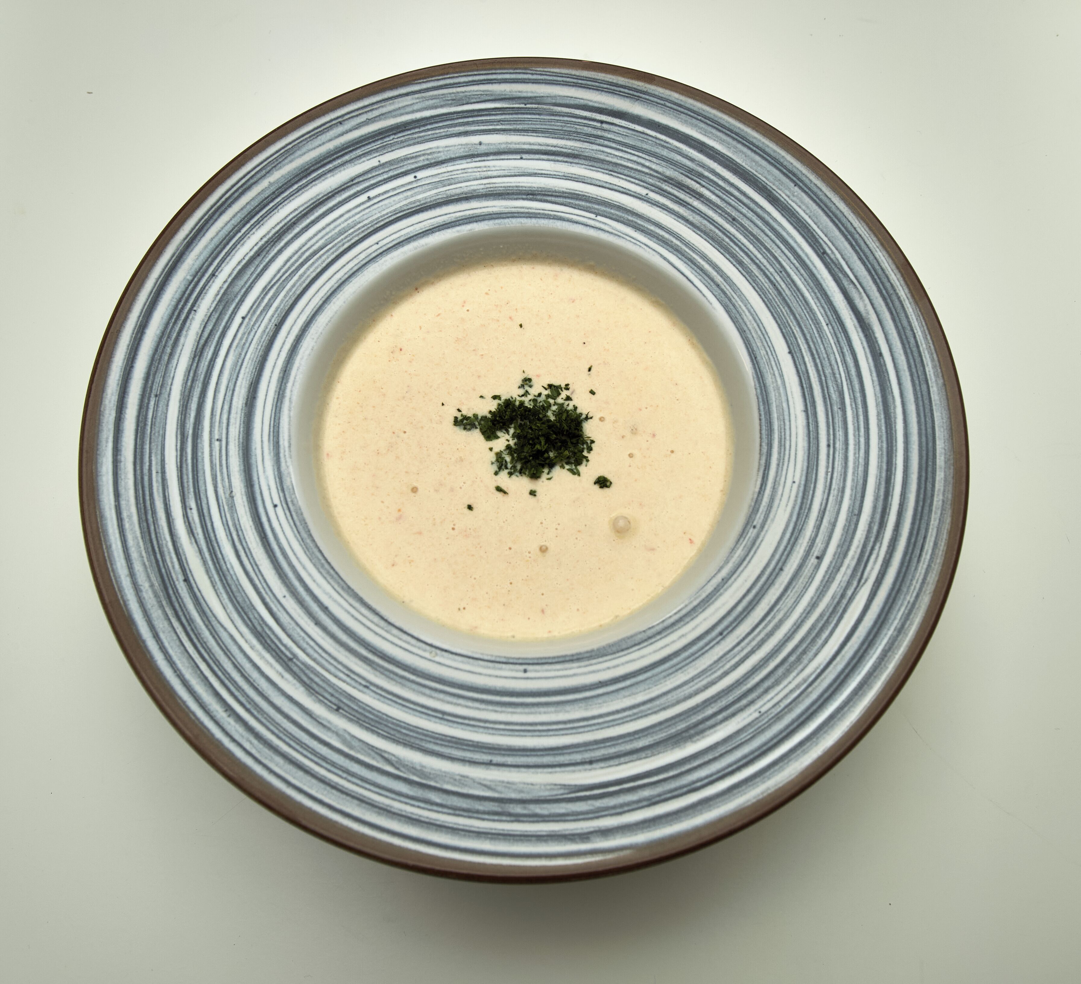 Un tazón de sopa con una guarnición en un plato.