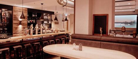 A bar area with stools, a bar counter, and a seating area with a table and benches.