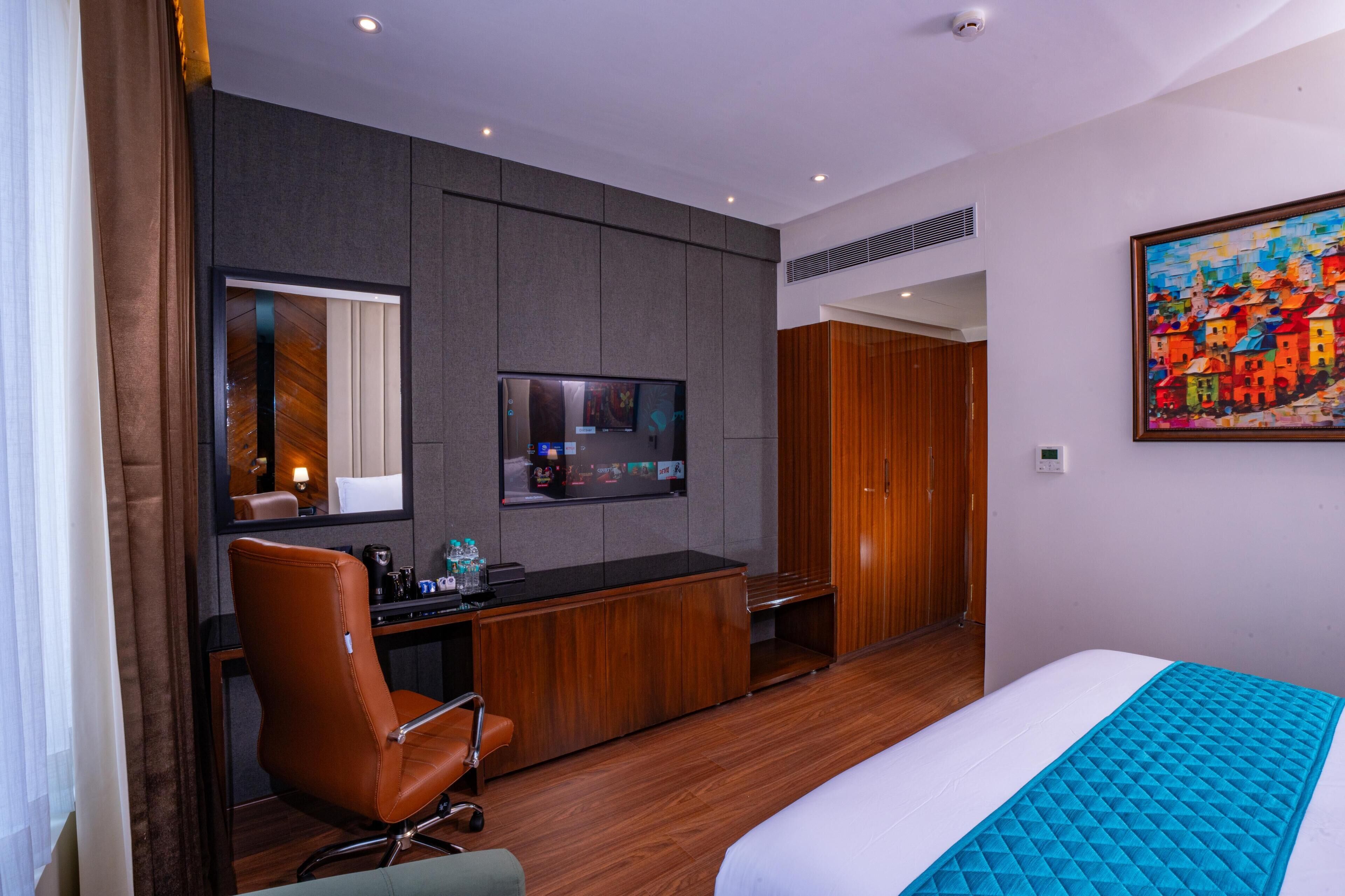 Una habitación de hotel con cama, escritorio, silla, televisión y armario.
