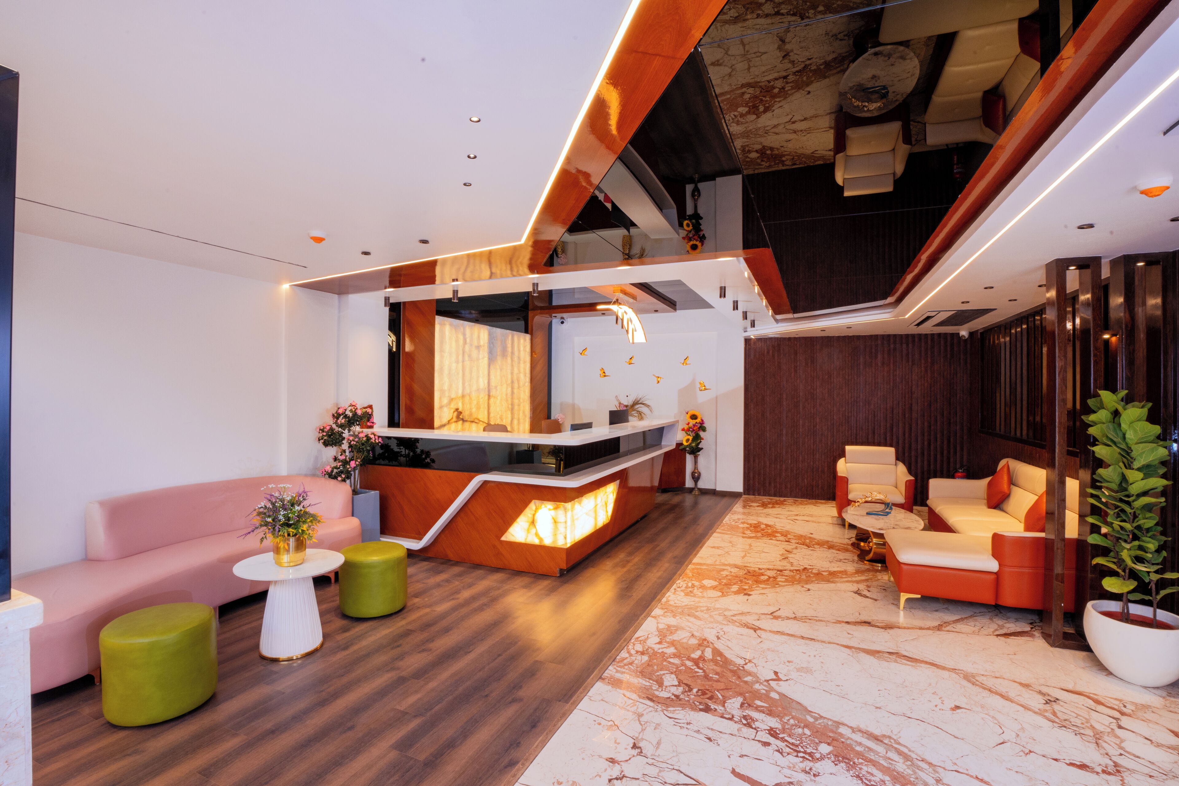 A modern lobby with a reception desk, seating area, and a staircase.
