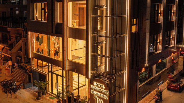 A modern hotel with a glass facade, multiple balconies, and a sign indicating it is Hotel Paramos. - Hotel Paramos Meeds (Bengaluru)
