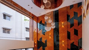 A modern interior with a wooden accent wall, a round ceiling light, and a seating area with a glass railing. - Hotel Paramos Meeds (Bengaluru)