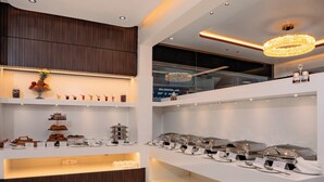 A modern, well-lit buffet area with marble flooring, wooden paneling, and a variety of food and drink options. - Hotel Paramos Meeds (Bengaluru)