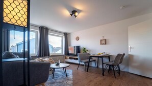 A modern living room with a sofa, coffee table, and dining area. - Cozy apartment fully equipped J&K Apartments (Kelheim)