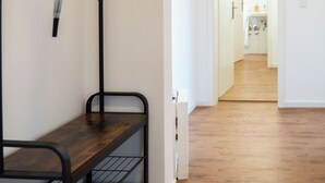 A hallway with a wooden bench, a water spout, and a view into a bathroom. - Cozy apartment fully equipped J&K Apartments (Kelheim)