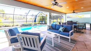 Un espace de vie extérieur doté d’une piscine, de sièges et d’un ventilateur de plafond.