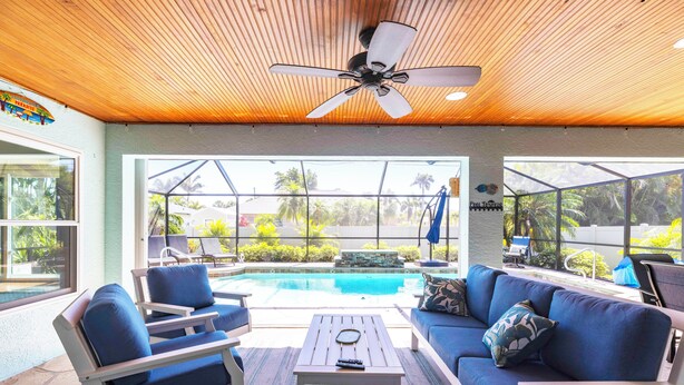 Un espace aménagé au bord de la piscine, doté d’un ventilateur de plafond, de sièges d’extérieur et offrant une vue sur la piscine.