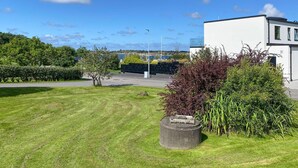 Un bâtiment moderne doté d’un toit plat et de grandes fenêtres, entouré de pelouses et d’arbustes bien entretenus.