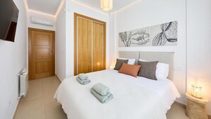 Une chambre d’hôtel avec un grand lit, une armoire en bois, un téléviseur à écran plat et des œuvres d’art murales.