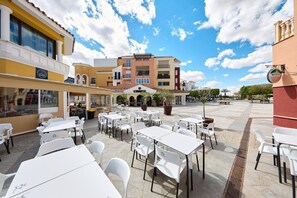 An outdoor cafe area with tables and chairs, a building with a 'BAR' sign, and a clear blue sky. - Casa del Sol La Torre Golf Resort (Torre-Pacheco)