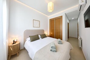 A modern hotel room with a large bed, a bedside table, a wardrobe, and a radiator. - Casa del Sol La Torre Golf Resort (Torre-Pacheco)