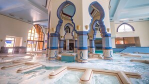 A large indoor swimming pool with multiple lanes, surrounded by decorative pillars and arches. - Stayr Somabay - Bay life home rentals (Soma Bay)