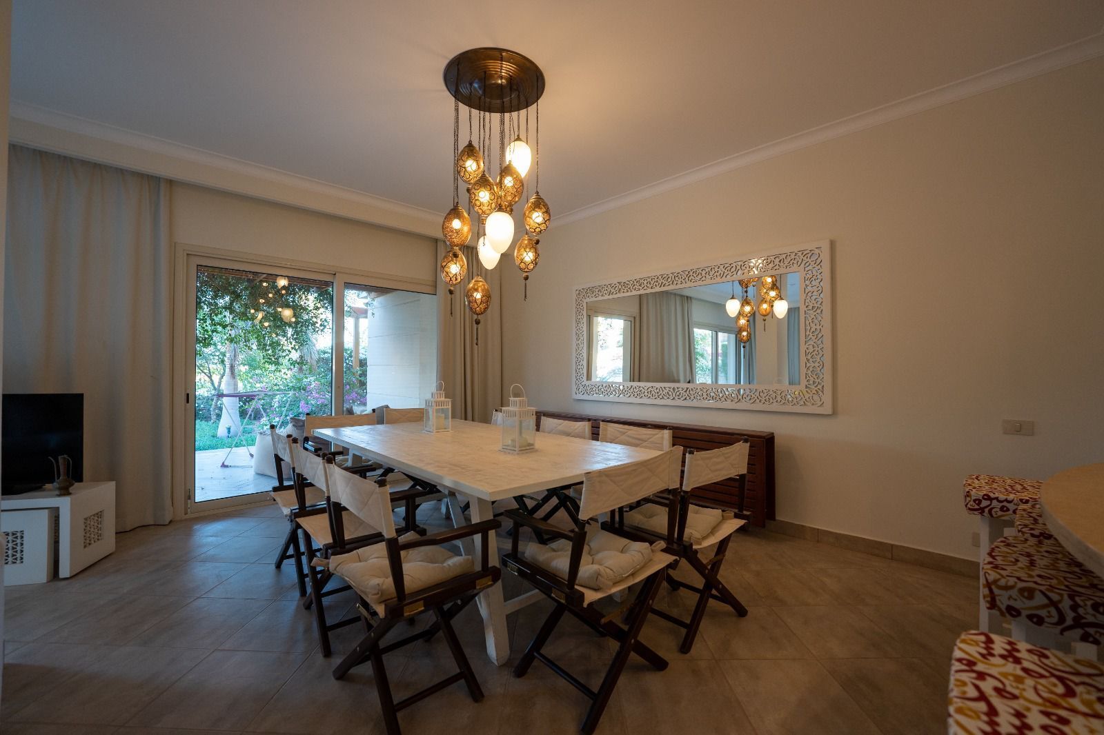 A dining area with a large table, chairs, and hanging lights.