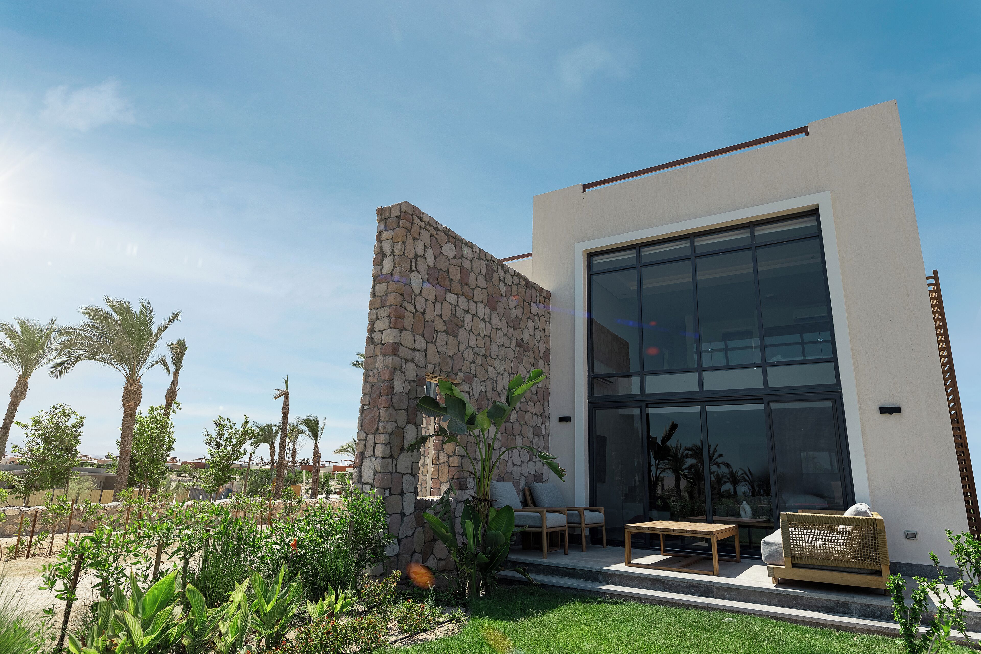 A modern building with a stone facade, large windows, and outdoor seating.