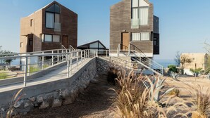A modern building with a stone staircase leading to a flat roof, surrounded by desert vegetation. - Stayr Somabay - Bay life home rentals (Soma Bay)