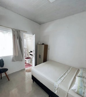 Un dormitori amb un llit, un armari, una cadira i un lavabo.