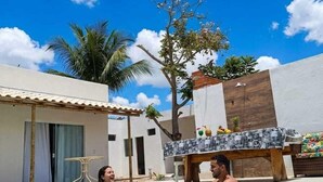 A swimming pool with a tiled deck, a wooden bench, and a palm tree in the background.