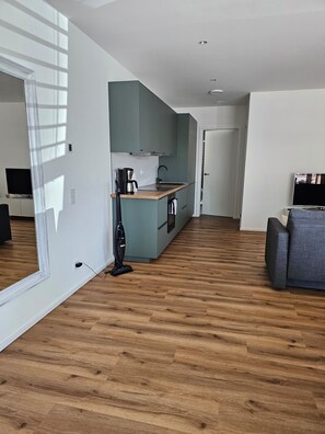 Een modern appartement met keuken, zithoek en een grote spiegel.