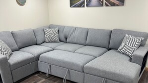 A grey sectional sofa with a wooden floor. - Charming pet friendly 1-bedroom apartment with WiFi, AC in quaint Conneaut Lake (Conneaut Lake)
