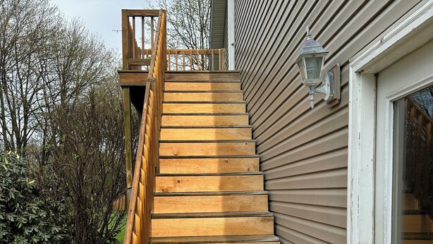 A wooden staircase leading to a house with a white door and a light fixture above it. - Charming pet friendly 1-bedroom apartment with WiFi, AC in quaint Conneaut Lake (Conneaut Lake)