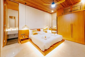 Ein modernes Schlafzimmer mit Holzboden, einem großen Bett mit weißer Bettwäsche, Nachttischen und einem Kleiderschrank.