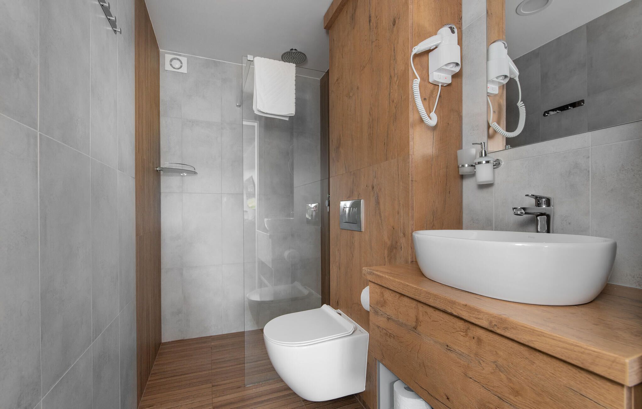 A modern bathroom with a shower, toilet, and sink.