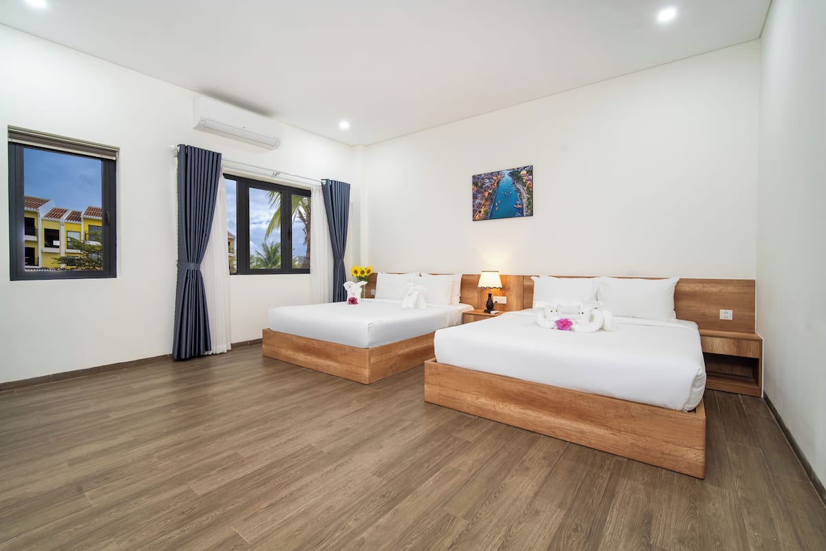 Habitación de hotel con dos camas, cabeceros de madera, un cuadro en la pared y una ventana con cortinas.