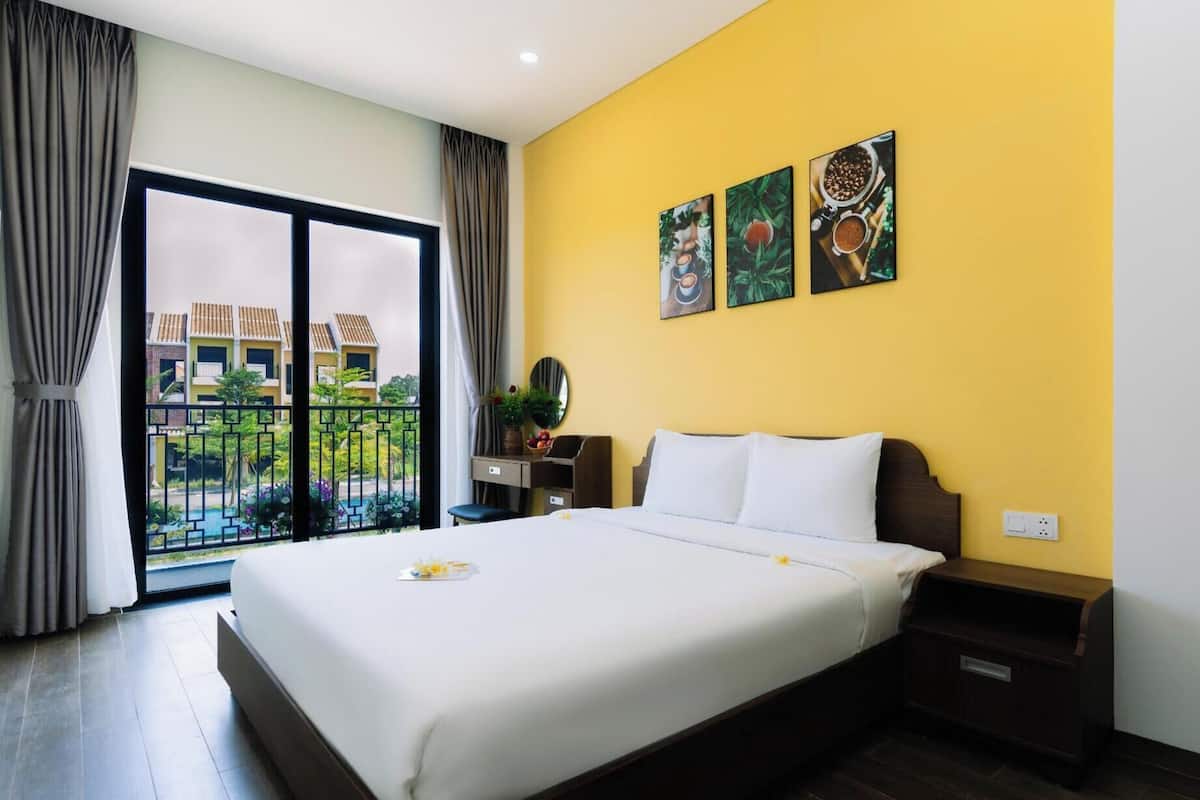 Habitación de hotel con una cama grande, una mesita de noche, un escritorio y vistas a un patio a través de una puerta corredera.