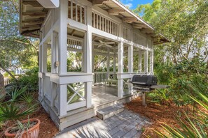 A covered outdoor area with a grill, wooden deck, and surrounding vegetation. - Seabatical: 3BR Dog-Friendly Beach House Retreat for 8 in Carillon Beach (Panama City Beach)