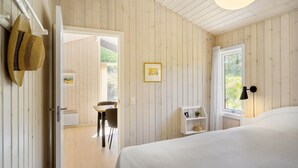 A bedroom with a bed, a desk, and a chair. There is a window with a view of greenery outside. - 3 bedroom beautiful home in Blokhus (Blokhus)