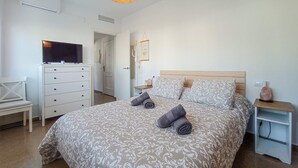 Une chambre à coucher avec un lit, une télévision, une commode et une table de chevet.