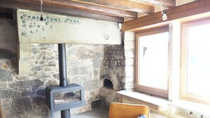 Una chimenea de piedra con inserto moderno, una ventana con marco de madera y un sillón amarillo.