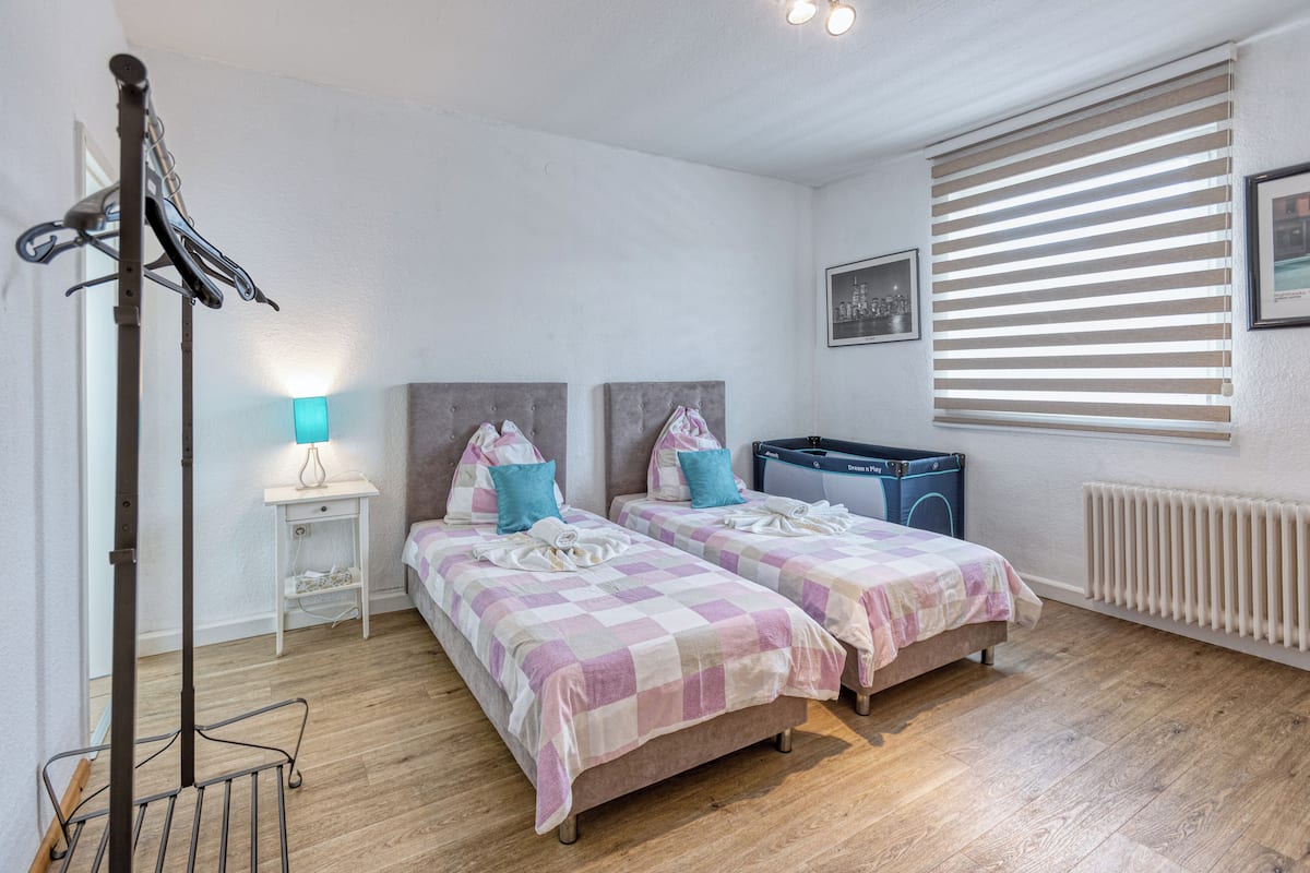 Ein Schlafzimmer mit zwei Betten, einem Heizkörper, einer Waschmaschine und einem Wäscheständer.