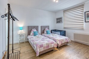 A bedroom with two beds, a radiator, a washing machine, and a drying rack. - Touch Down Motel (Lohmar)