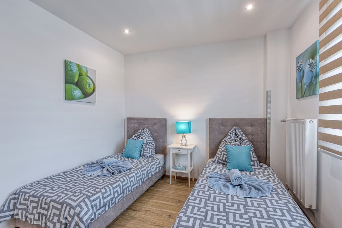 Ein Zimmer mit zwei Betten, einem Nachttisch, einer Lampe und Bildern an den Wänden.