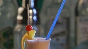 Ein Cocktail im Glas mit Trinkhalm und einer Kirsche.
