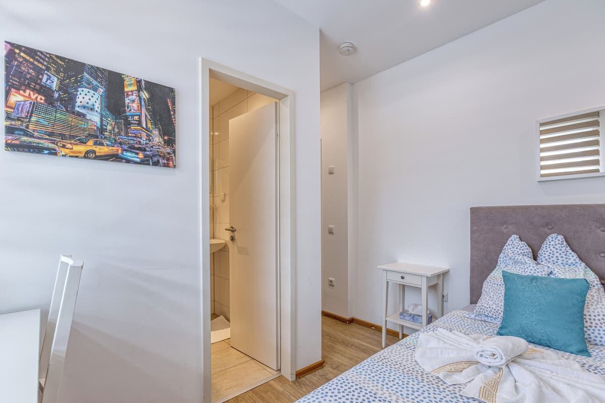 Ein Hotelzimmer mit Bett, Nachttisch, Badezimmer mit Dusche und einem Stadtbild.