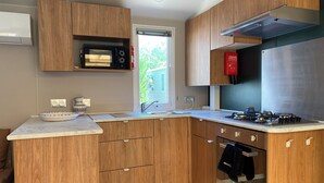 Una cocina moderna con armarios de madera, microondas integrado, campana extractora de acero inoxidable y estufa a gas.