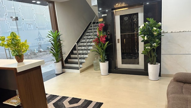 Un hall d’entrée moderne avec un escalier, des plantes en pot et un comptoir d’accueil.
