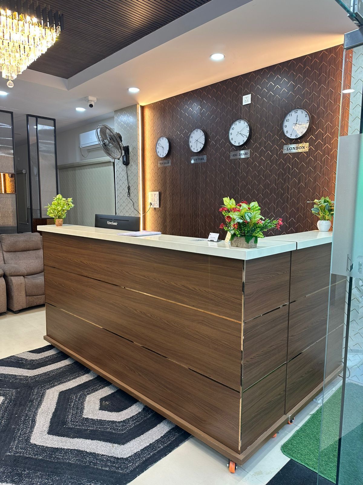 A reception desk with a wooden finish, multiple clocks displaying different time zones, and a modern chandelier.