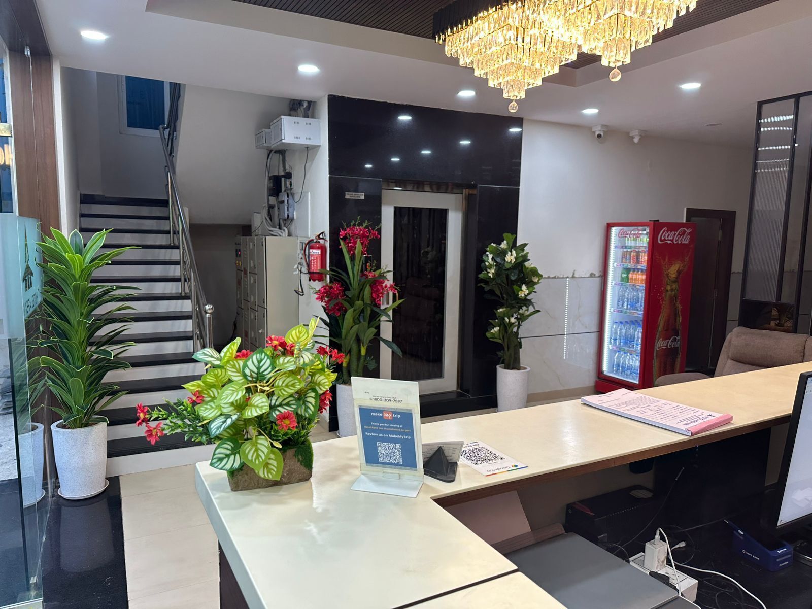 A reception desk with a plant, a sign, and a Coca-Cola refrigerator.