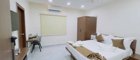 A hotel room with a bed, a desk, a wardrobe, and a ceiling fan.