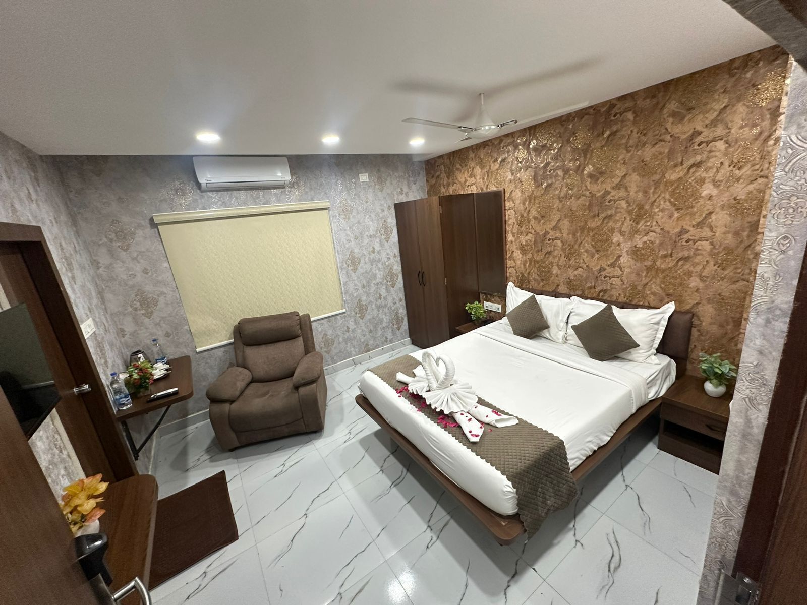 A hotel room with a bed, a chair, a wardrobe, and a window.