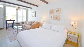 A bedroom with a large bed, a sofa, a small table, and a lamp.