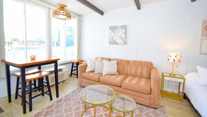A cozy living room with a sofa, a glass coffee table, a wooden dining table, and a lamp.
