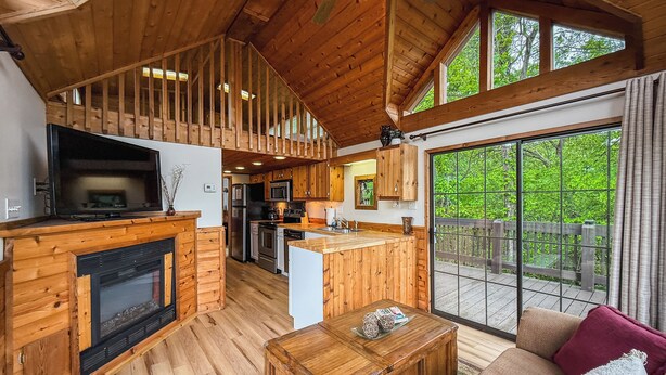 A spacious living area with a fireplace, wooden furniture, and a large window offering a view of the outdoors.
