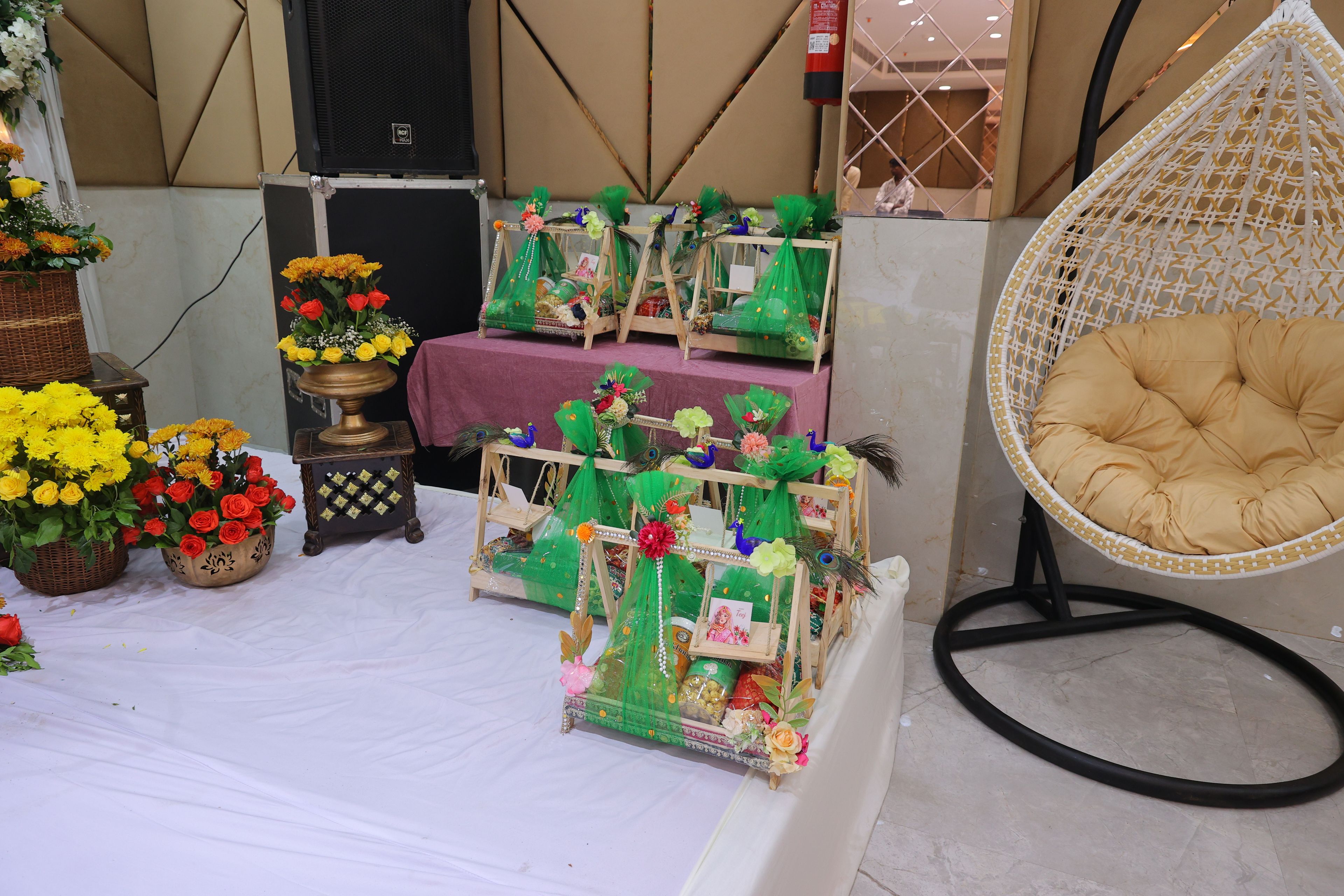 A room with a stage area, a hanging chair, and various decorative items including flowers and a peacock.