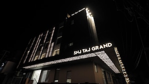 A building with the sign 'SNJ Taj Grand' illuminated at night. - SNJ TAJ GRAND HOTEL (Agra)
