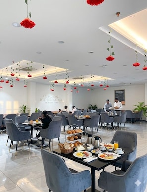 A modern restaurant with breakfast service, featuring a clean interior, grey chairs, and tables set with breakfast items. - SNJ TAJ GRAND HOTEL (Agra)