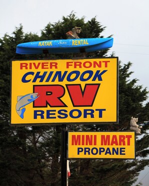 A sign for River Front Chinook RV Resort with a kayak rental and Mini Mart propane sign.